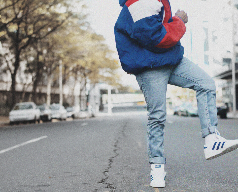 A 90s-style photograph of a teenage boy dancing in an empty street.